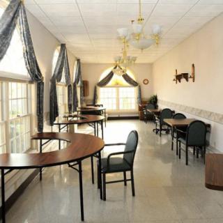 A spacious dining room with several tables and chairs, decorated with elegant curtains and chandeliers.