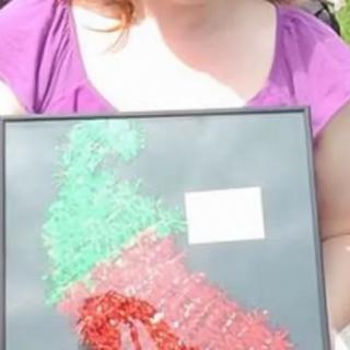 A child holding a framed colorful artwork depicting abstract shapes.