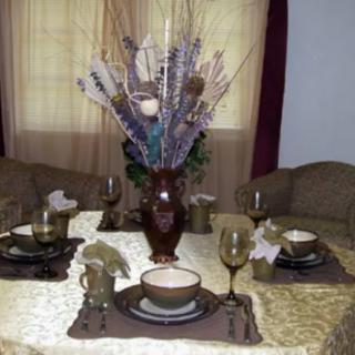 A dining table set with an elegant centerpiece, featuring arranged plates, glasses, and napkins for a formal meal.