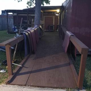 A wooden ramp leading to the entrance of a house, with evening lighting.
