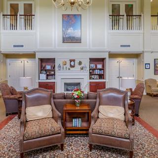 A cozy living room with elegant furniture, a central fireplace, bookshelves, and decorative elements.