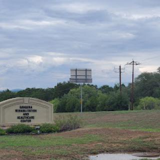 A scenic view featuring a roadside sign and a distant water tower under a cloudy sky.