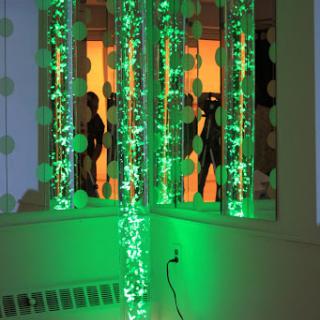 A vibrant display of green lights creates an artistic atmosphere as silhouettes are reflected in the background.