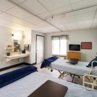 A hospital room with two beds and medical equipment.