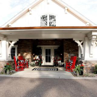 A charming front porch with red rocking chairs and decorative plants.