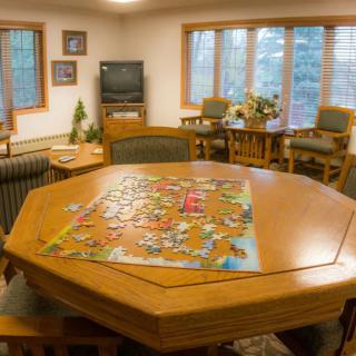 A cozy living room with a puzzle set up on an octagonal table.