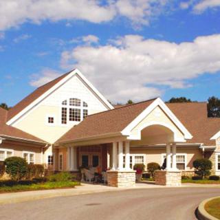 A suburban residential building with a large driveway and partly cloudy skies.