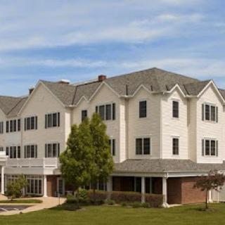 A modern three-story residential building with a landscaped lawn.