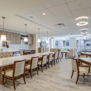 A modern and spacious kitchen and dining area with elegant lighting fixtures and seating.