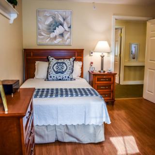 A cozy bedroom with a neatly made bed, nightstand, and lamp.