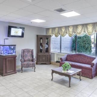A cozy waiting room featuring plush seating, a television, and an aquarium.