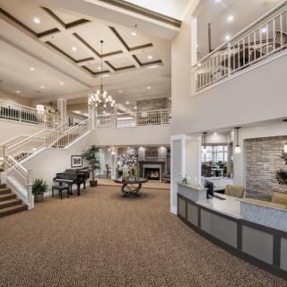 A modern and spacious lobby featuring a grand staircase, chandelier, and reception area.
