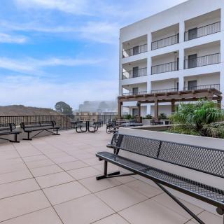 A spacious outdoor patio area with benches and a view of a modern building under a clear blue sky.