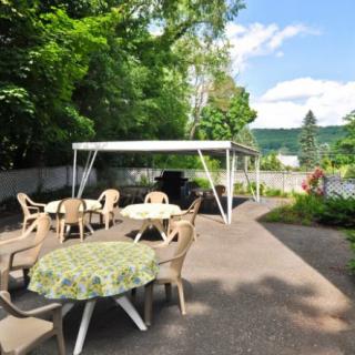 A sunny outdoor patio with tables, chairs, and a gazebo surrounded by greenery.