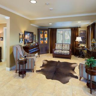 A cozy living room featuring a patterned sofa, armchairs, and a dark animal-hide rug.