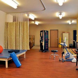 A well-equipped exercise room with various fitness and therapy equipment.