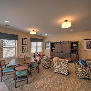 A cozy living room with comfortable seating and a table, featuring warm decor and ambient lighting.