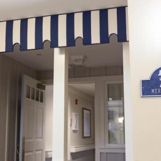An interior hallway with a blue and white striped awning above the entrance.