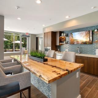 A modern kitchen with a wooden countertop and bar seating, featuring an open and well-lit design.