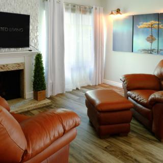 A cozy living room featuring leather furniture, a fireplace, and decorative artwork.