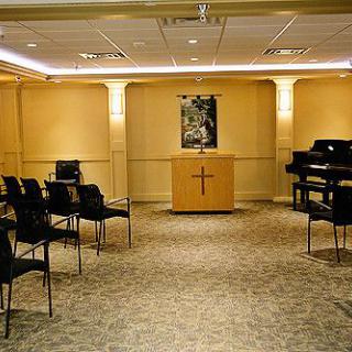 A small chapel with seating, an altar, and a piano.