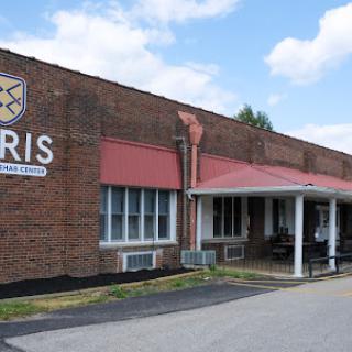 An exterior view of a brick school building featuring large windows and a canopy entrance.