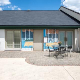 A small building with a patio featuring a table and chairs, under a clear blue sky.