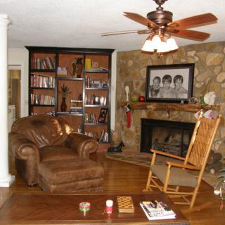 A cozy living room with a fireplace, armchair, and bookshelf.