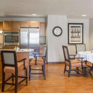 A modern kitchen and dining area with wooden flooring, featuring a countertop, chairs, and dining table.