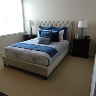A stylish modern bedroom featuring a comfortable bed with blue and white bedding, accented by decorative pillows and bedside lamps.