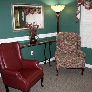 A cozy living room corner with two armchairs, a floor lamp, and a decorative mirror.
