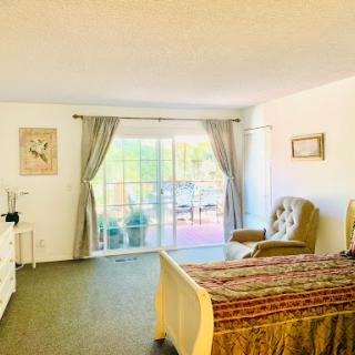 A cozy bedroom featuring a comfortable bed, elegant curtains, and a charming view through the sliding glass door.
