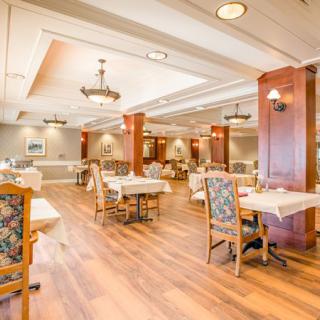 A spacious and elegantly designed restaurant dining area with wooden floors, tables, and chairs.
