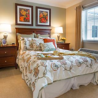A cozy and well-decorated bedroom with a neatly made bed, bedside tables with lamps, and artwork above the headboard.