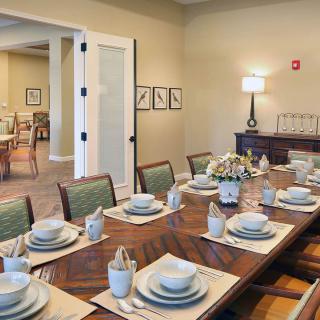 A well-appointed dining room with a wooden table set for a formal meal, featuring matching plates, cups, and neatly folded napkins.