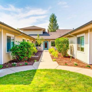 A serene courtyard with lush greenery and a central pathway leading to the house.