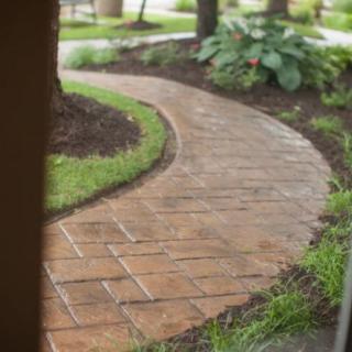A curved brick pathway winds through a landscaped garden.