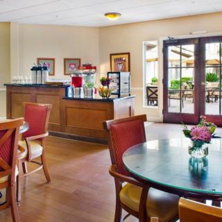 A cozy dining area with tables, chairs, and a coffee station, adorned with decorative flowers.