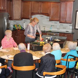 A group of seniors attending a cooking class in a kitchen setting.