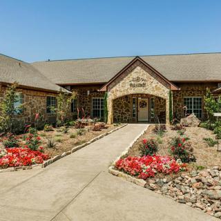 A stone building with a landscaped entrance and colorful flowers.