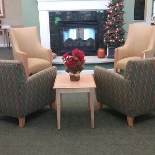 A cozy seating area with armchairs and a coffee table near a fireplace, decorated with a Christmas tree.