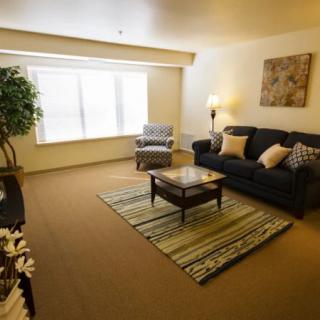 A cozy living room with a dark sofa, coffee table, and an armchair near a large window.