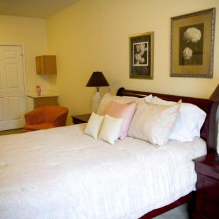 A cozy bedroom interior featuring a neatly made bed, wall art, and a lamp.
