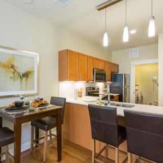 A modern kitchen and dining area featuring sleek appliances, wooden cabinetry, and stylish lighting.
