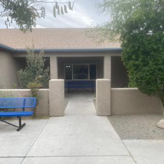 A building entrance with a pathway and benches surrounded by trees.