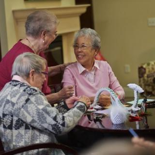 A group of seniors socializing and engaging in a hobby indoors.