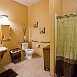 A well-organized bathroom with tan walls and a green shower curtain.