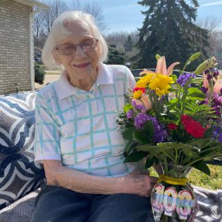 A joyful elderly woman enjoying a beautiful bouquet of spring flowers outdoors.