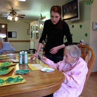A caregiver assists elderly residents during an activity at a nursing home.