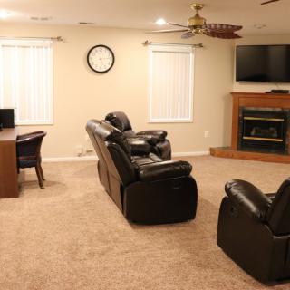 A cozy living room with leather seating, a fireplace, and a television.